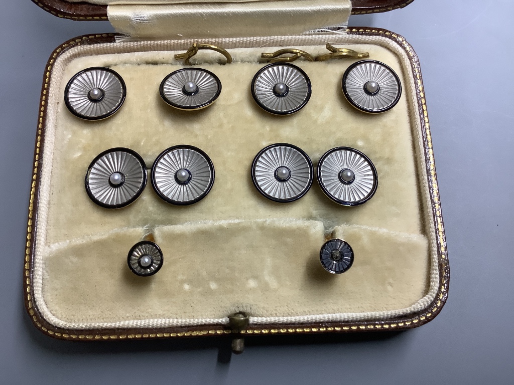An Edwardian 18ct. gold and platinum, black enamel and pearl, eight piece cuff links, stud and button set, cased